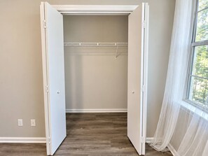 A walk-in closet with a wooden floor, a hanging rod, and a window with sheer curtains. - Modern Top-Floor Loft w/ Pool, Balcony & Garden View! (Wilmington)