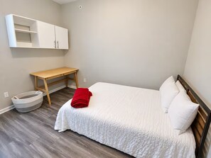 A bedroom with a bed, a wooden desk, and a white wardrobe. - Modern Top-Floor Loft w/ Pool, Balcony & Garden View! (Wilmington)