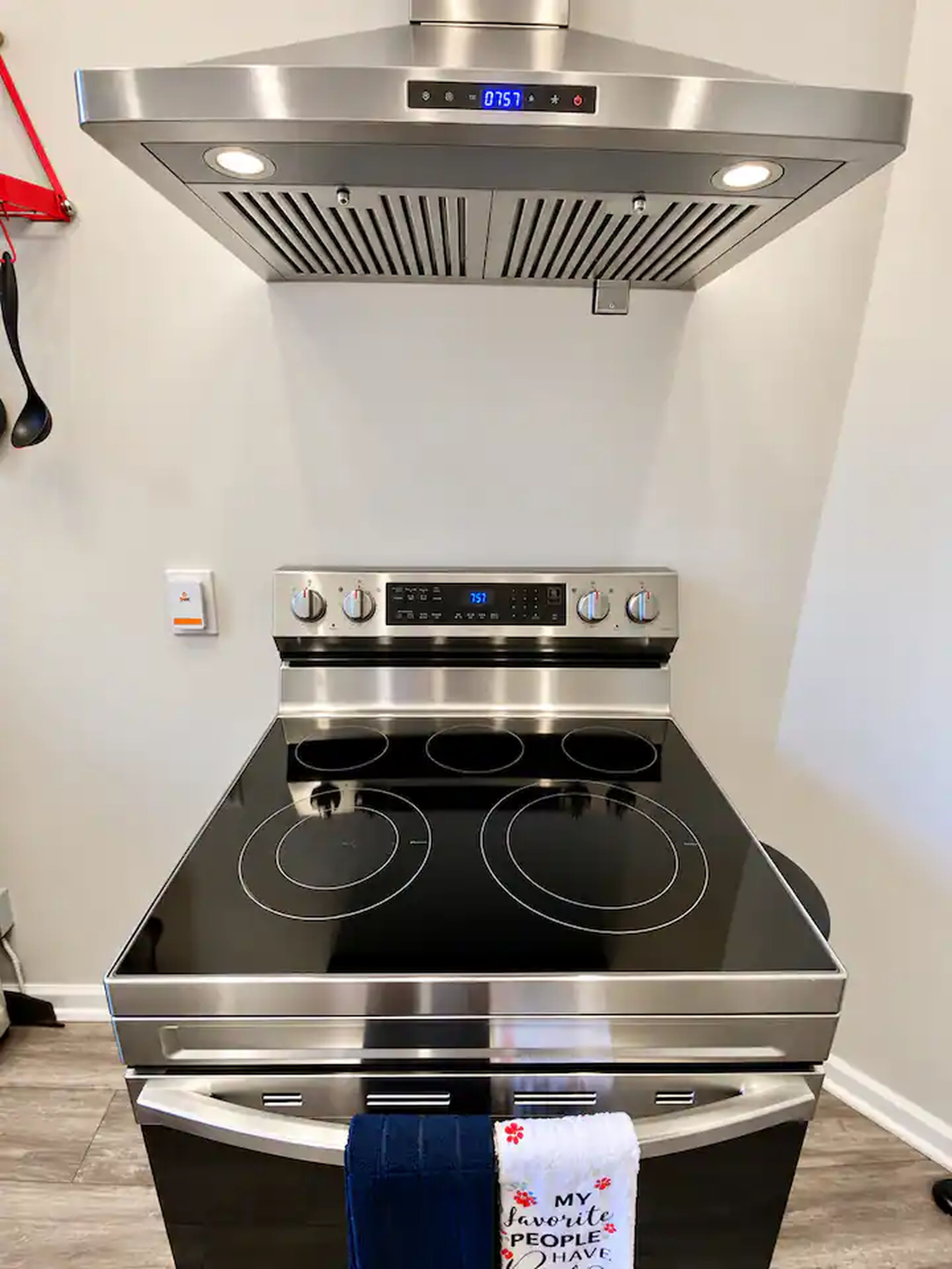 A stainless steel range hood with a digital display above a black stovetop oven.