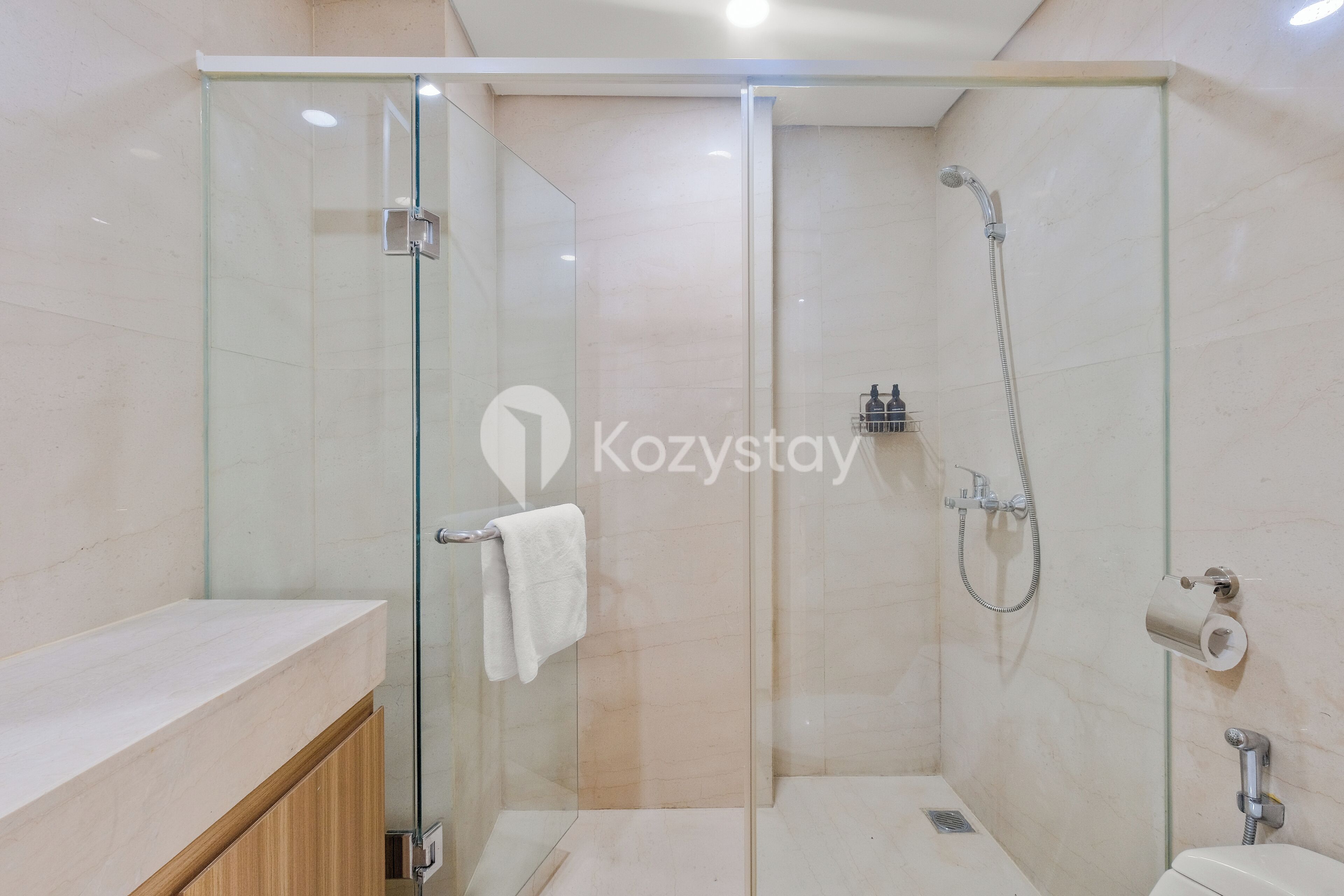 Un baño moderno con ducha de vidrio, inodoro y lavamanos, con una toalla colgada en la pared.