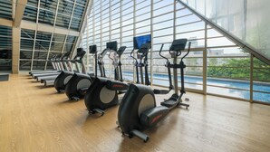 Un gimnàs amb equips cardiovasculars i un gran finestral amb vista a una piscina.