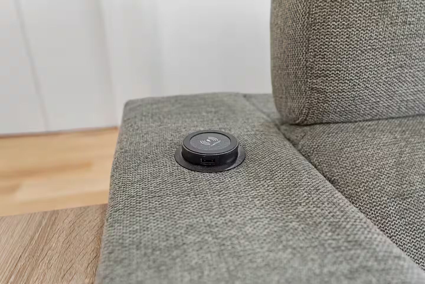 En grå soffa med ett svart föremål på sig.