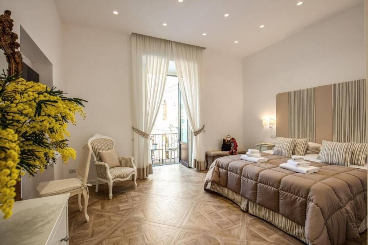 A hotel room with a large bed, a chair, a desk, and a view of the outside.