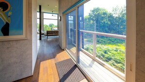 A modern hotel corridor with large windows, a wooden floor, and a poster on the wall. - Off Piste Chalet (Kutchan)