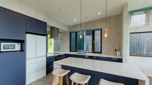 A modern kitchen with a large island, bar stools, and a microwave. - Off Piste Chalet (Kutchan)