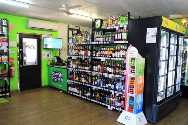 Une boutique de boissons alcoolisées avec des étagères remplies de bouteilles de toutes sortes et un réfrigérateur.