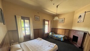 Ein Hotelzimmer mit einem großen Bett, einer kleinen Couch, einem Kamin und zwei mit Vorhängen versehenen Fenstern.