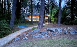 A lodge surrounded by tall trees, with a pathway leading to the entrance.