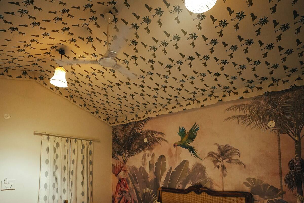 Un dormitorio con cama de madera, ventilador de techo y un mural de fauna tropical.