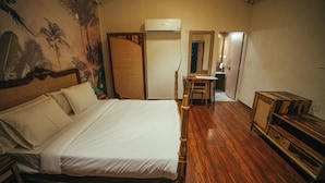 A room with a wooden bed, a wooden dresser, a chair, a desk, and a mirror. - Vanantara Courtyard (Alwar)