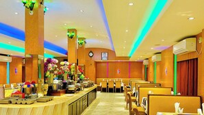 Un vestíbulo de hotel con un mostrador de recepción de mármol, un área de descanso y arreglos florales decorativos.