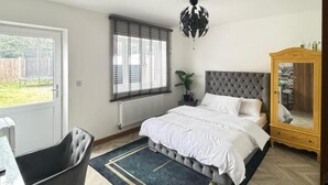 Quarto com cama grande, guarda-roupa de madeira, ventoinha no teto e janela com persianas.