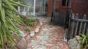 Un sendero de piedra que conduce a una cabaña de madera con una reja de metal.