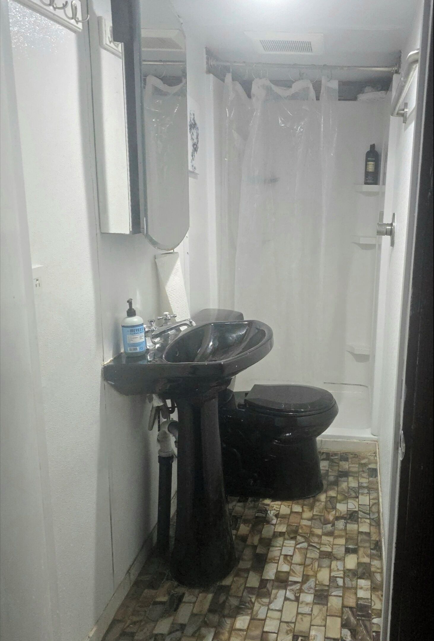 A bathroom with a black sink, toilet, and shower curtain.