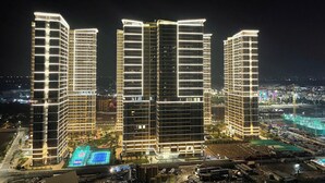 Un complesso di edifici a più piani con ampie finestre e una facciata ben illuminata di notte.