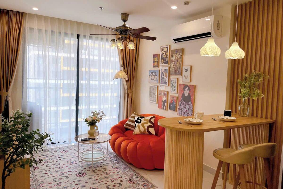 A modern living room with a red sofa, a wooden dining table, and a ceiling fan.