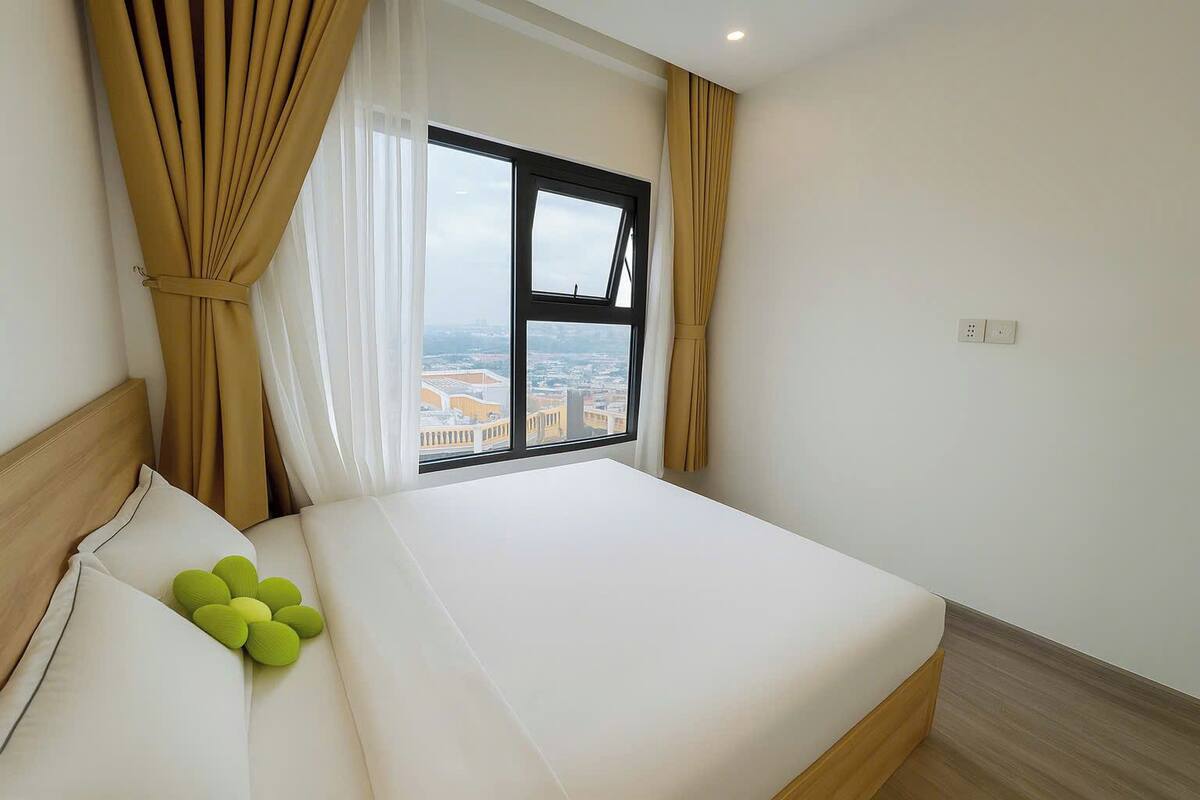 A hotel room with a bed, a view of the city through a window, and a cityscape visible outside.