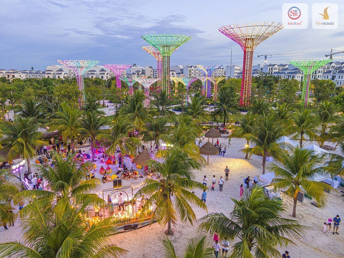 Zona de playa con palmeras y un escenario con gente.