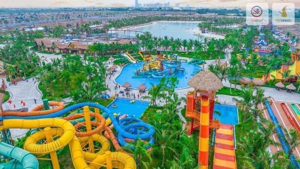 Un parco acquatico con diverse scivolate e piscine, immerso tra palme ed edifici.