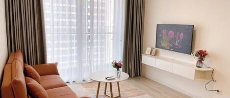 A modern living room with a brown leather sofa, a round coffee table, and a flat-screen TV mounted on the wall.