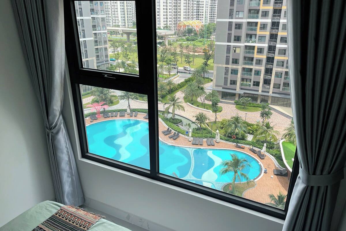 A room with a large window overlooking a swimming pool and a residential area.