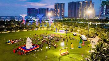 A park with a large open field, a pyramid-shaped fountain, and a stage for events.