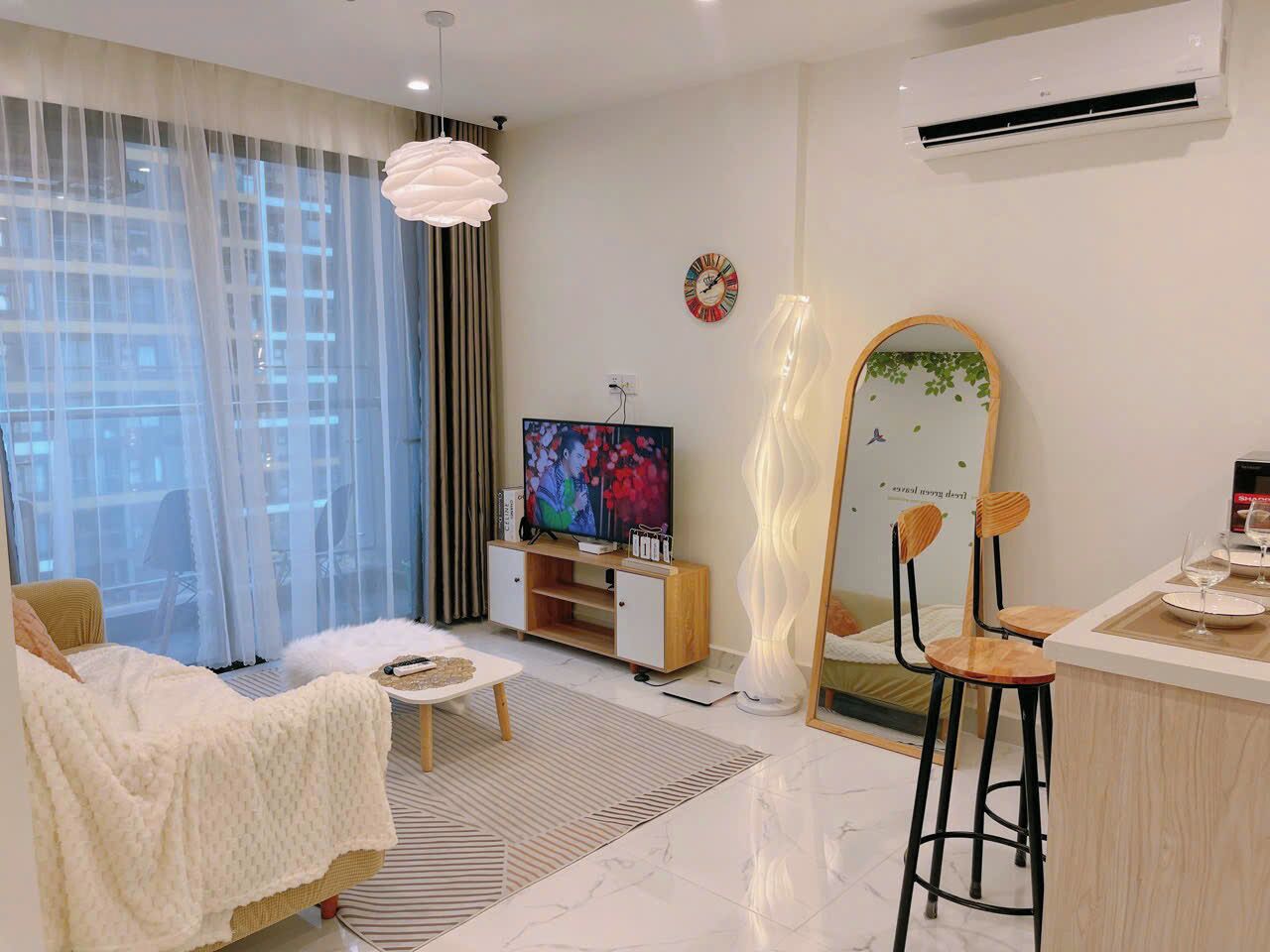 Una sala de estar moderna con un sofá, televisor y un comedor con taburetes.