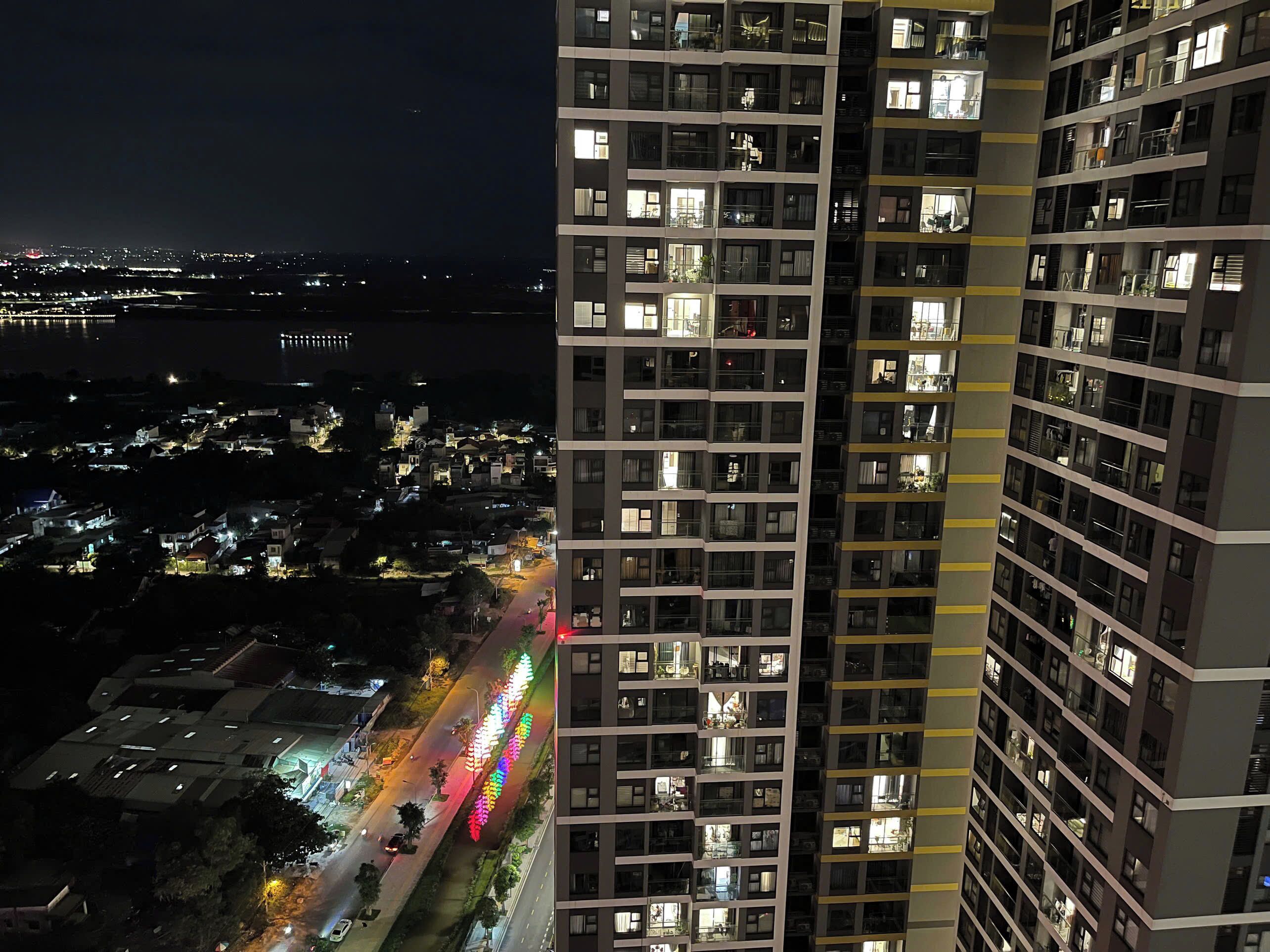 A high-rise building with multiple floors and balconies, surrounded by a cityscape at night.