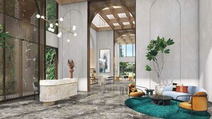 Spaziosa hall con reception, area salotto e ampie finestre che danno su spazi verdi.