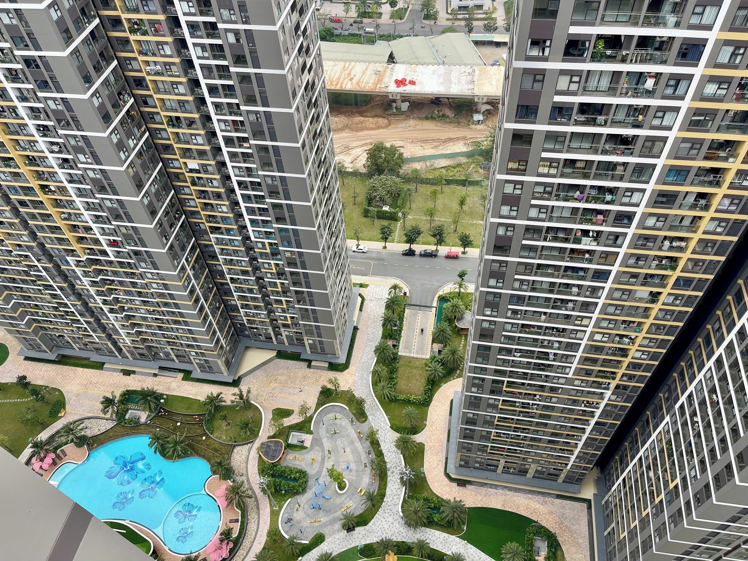 Un edificio residencial alto con varios balcones, piscina y áreas ajardinadas.