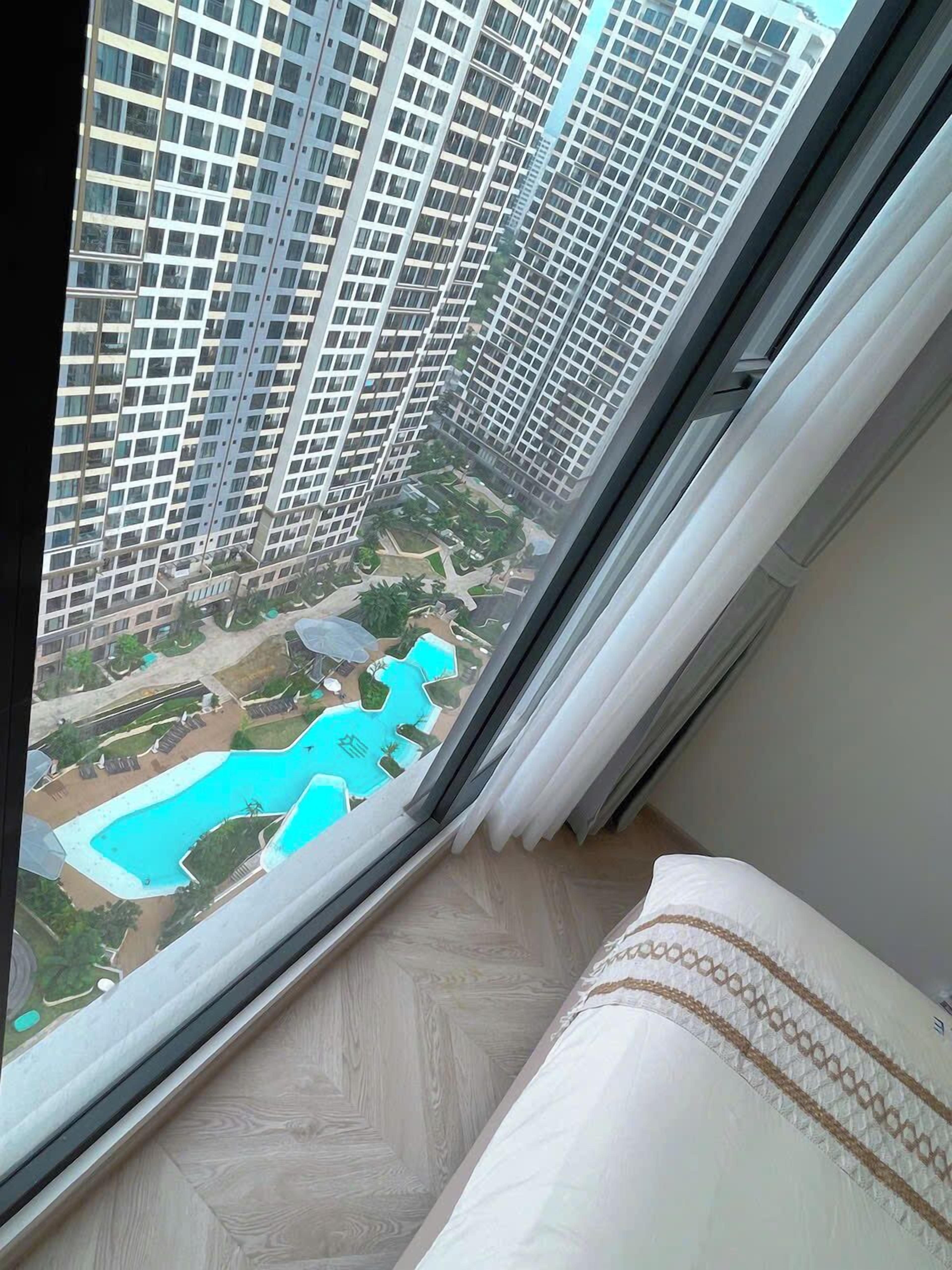 Un immeuble de grande hauteur offrant une vue sur une piscine et un espace verdoyant.