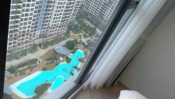 Un immeuble de grande hauteur offrant une vue sur une piscine et un espace verdoyant.