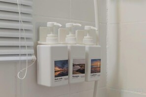 Eine wandmontierte Spenderstation mit Flaschen für Duschgel, Shampoo und Conditioner.