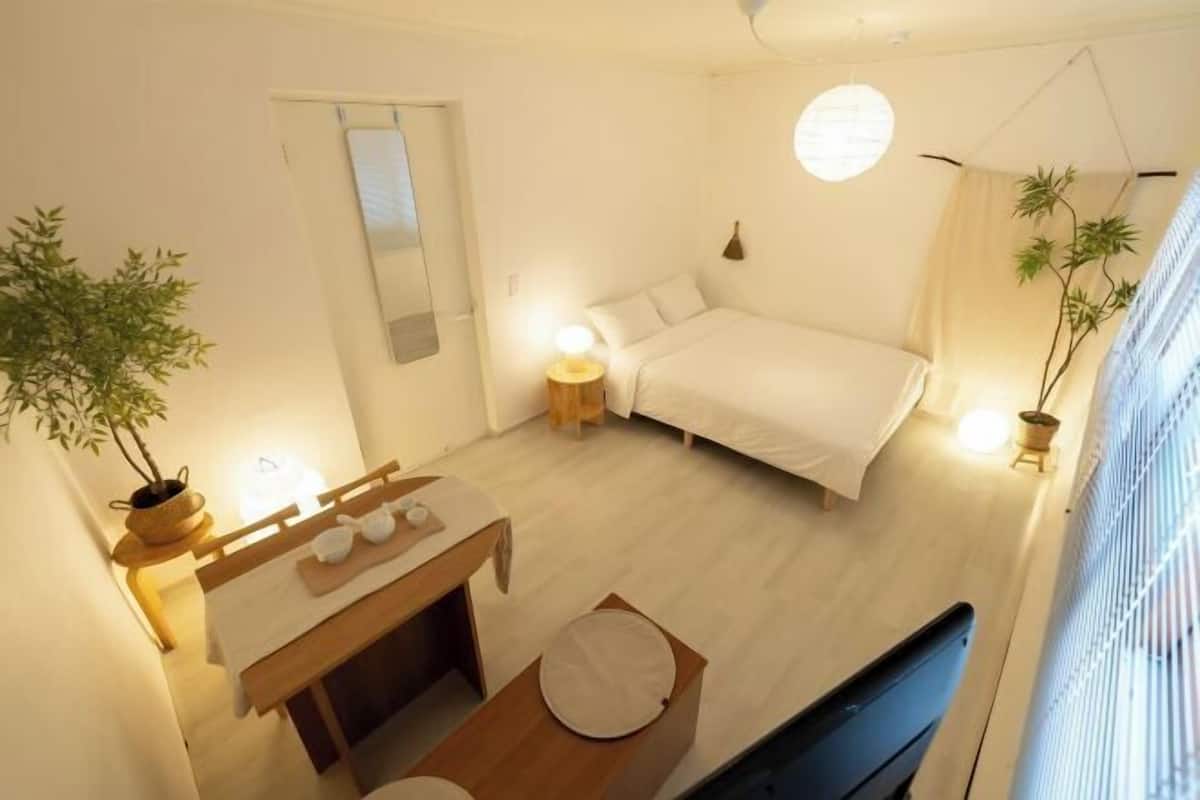 Ein Schlafzimmer mit Bett, Nachttisch, Lampe und einer Topfpflanze.