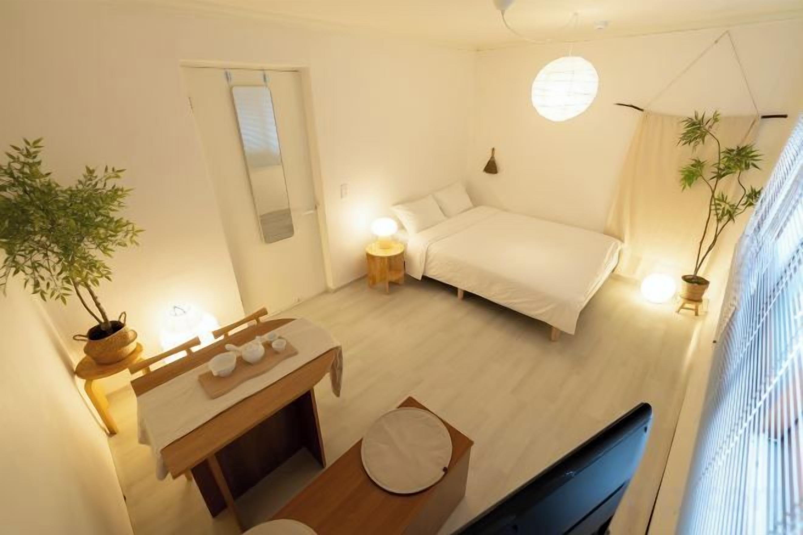 A bedroom with a bed, bedside table, and a potted plant.