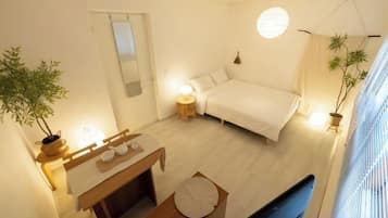 A bedroom with a bed, bedside table, and a potted plant.