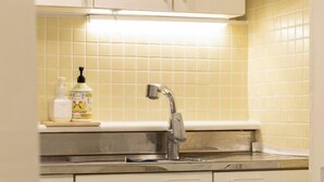 Una cocina con un lavamanos de acero inoxidable, un grifo y una encimera con dispensador de jabón.