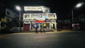 A two-story building with a brightly lit sign reading "The Gillard's." - Hotel Travellers Inn Sylhet (Sylhet)