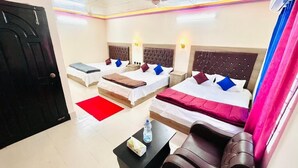 A hotel room with two beds, a red rug, a black coffee table, and a brown leather chair. - Hotel Travellers Inn Sylhet (Sylhet)
