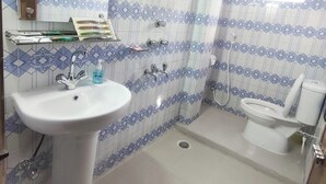 A bathroom with a pedestal sink, a toilet, and a shower. - Hotel Travellers Inn Sylhet (Sylhet)