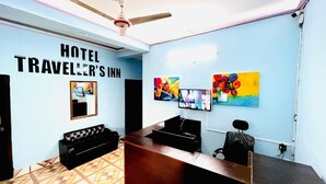 A hotel reception area with a reception desk, a sofa, a TV, and artwork on the walls. - Hotel Travellers Inn Sylhet (Sylhet)