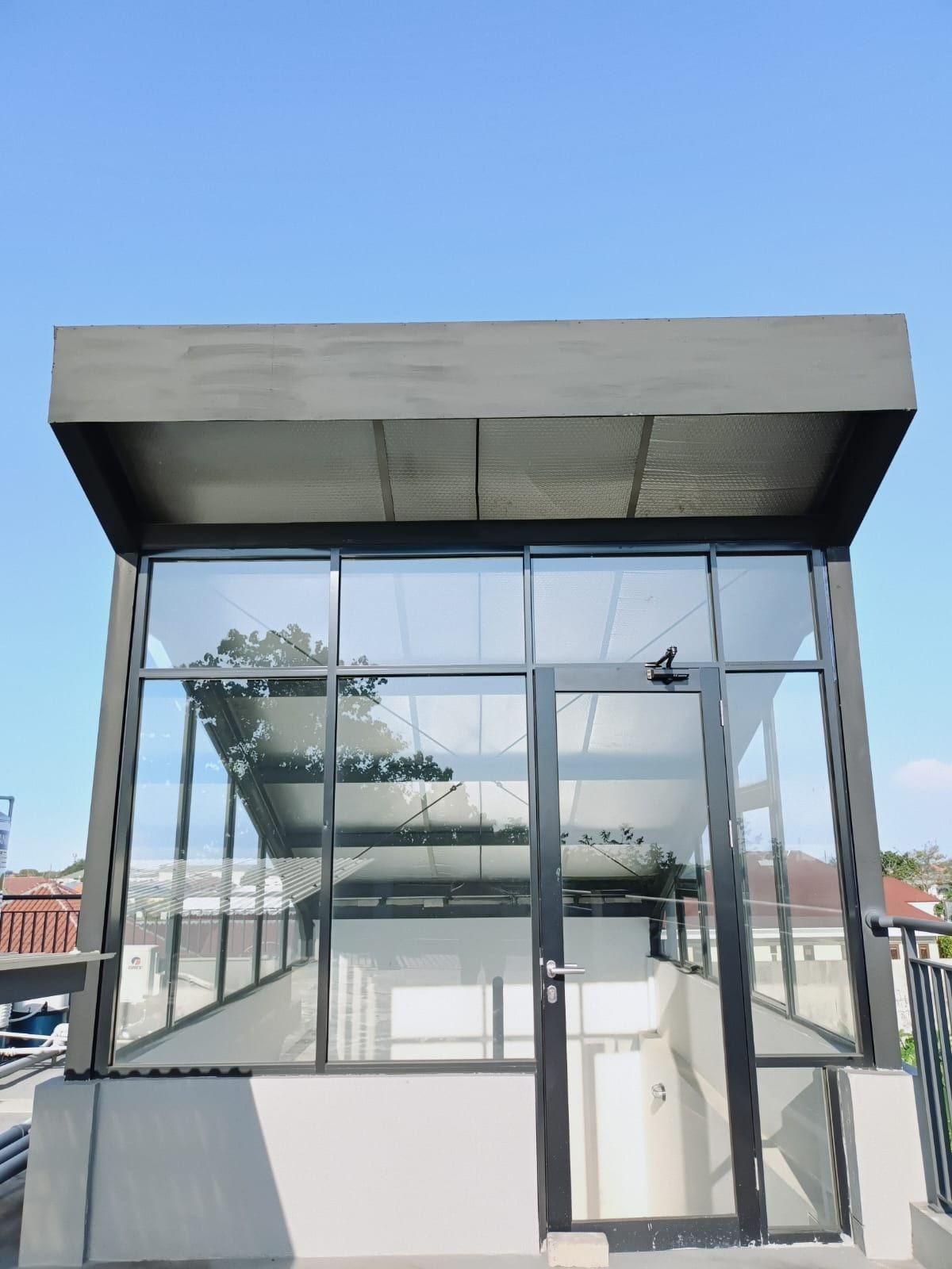 Ein modernes Gebäude mit Glasfassade, Metall-Dach und einer Tür mit Griff.