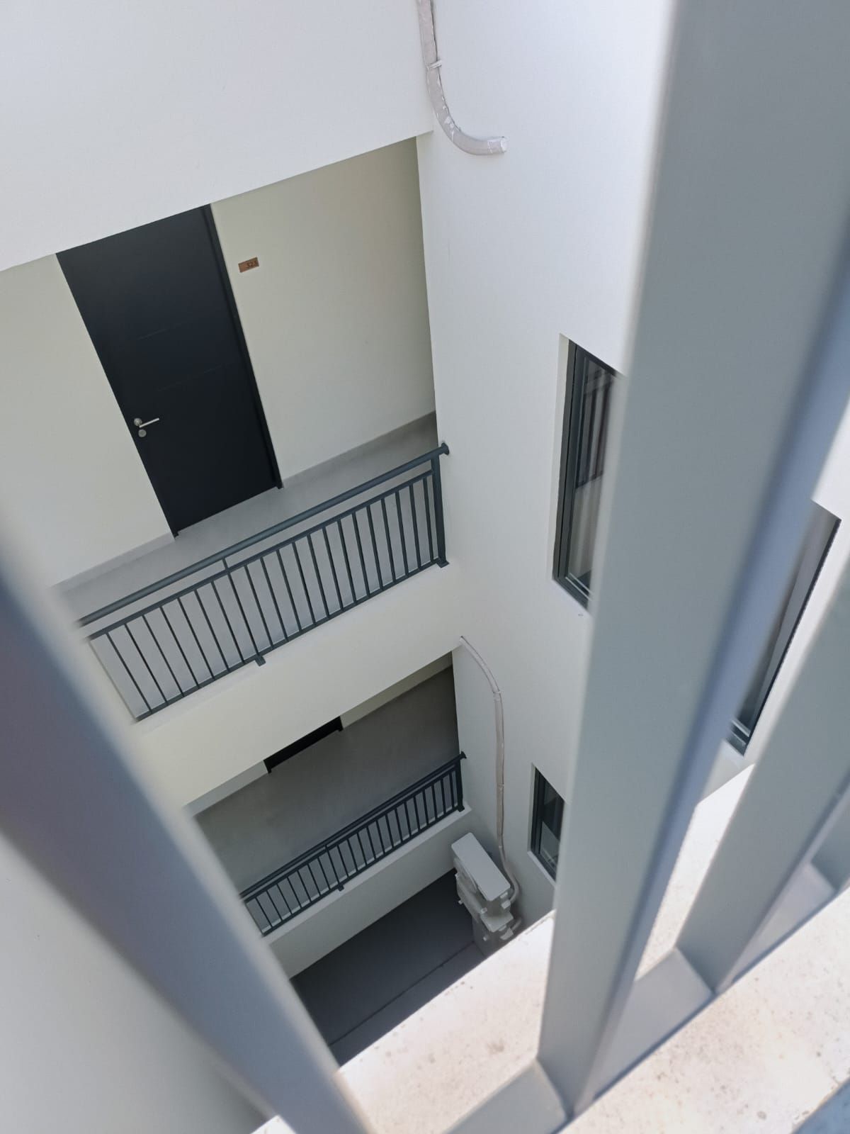 Un immeuble à plusieurs étages doté de balcons, d’une porte et d’une fenêtre.