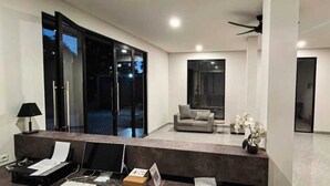 Ein modernes Wohnzimmer mit Glastür zum Balkon, einer Couch, einem Couchtisch und einer Lampe.