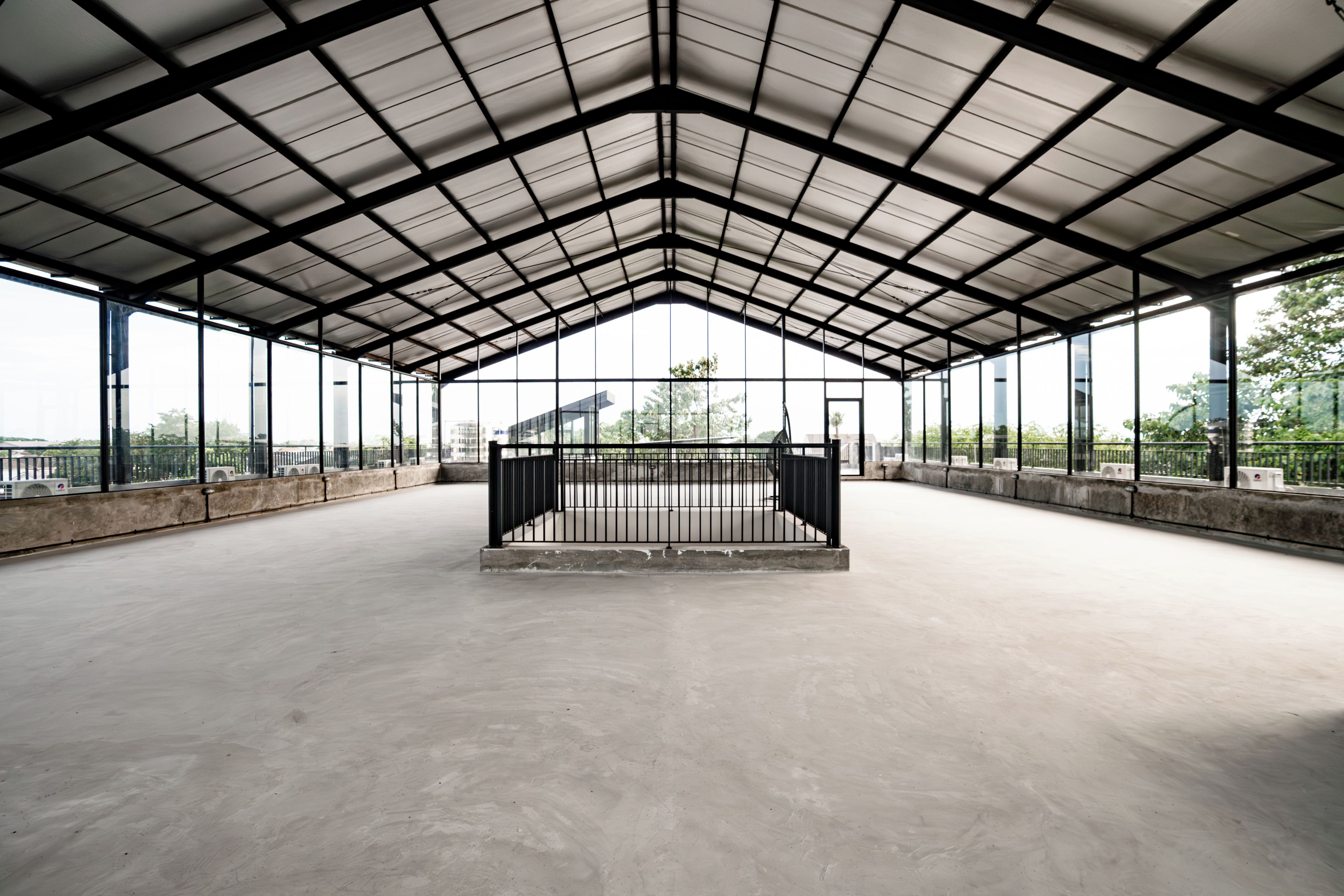 An indoor sports facility with a metal roof, large windows, and a concrete floor.