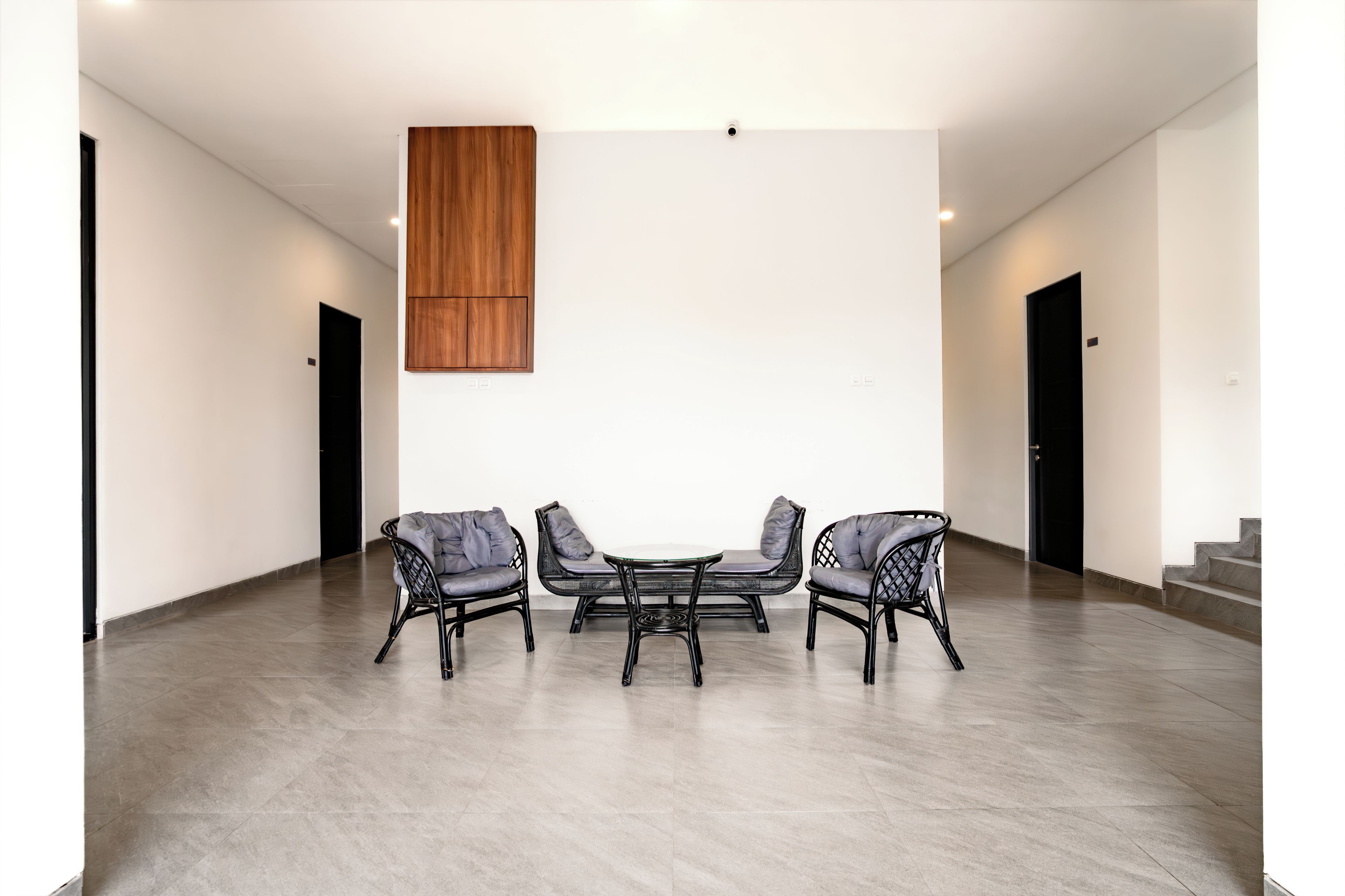 Une pièce spacieuse avec un plafond haut, un mur lambrissé en bois et un coin salon comprenant trois chaises et une table.