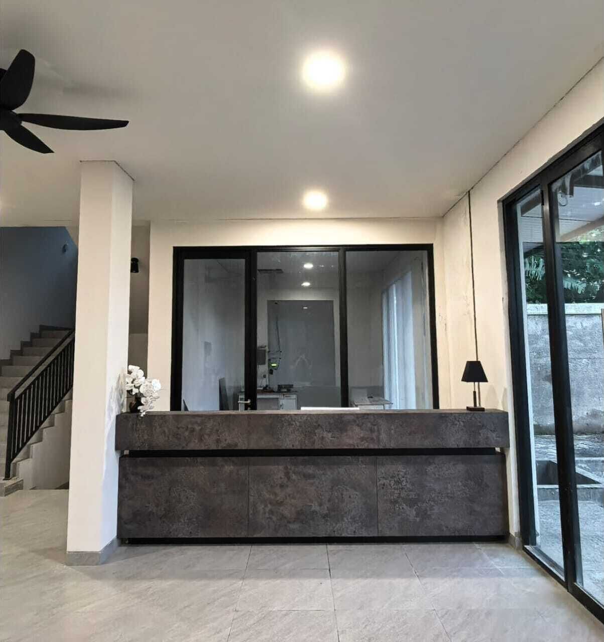 A modern reception area with a large sliding glass door, a ceiling fan, and a staircase to the left.