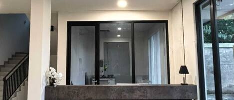 A modern reception area with a large sliding glass door, a ceiling fan, and a staircase to the left.