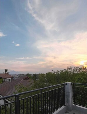 A balcony with a metal railing overlooking a residential area with houses and trees. - Shencasa Living Juanda (Sidoarjo)