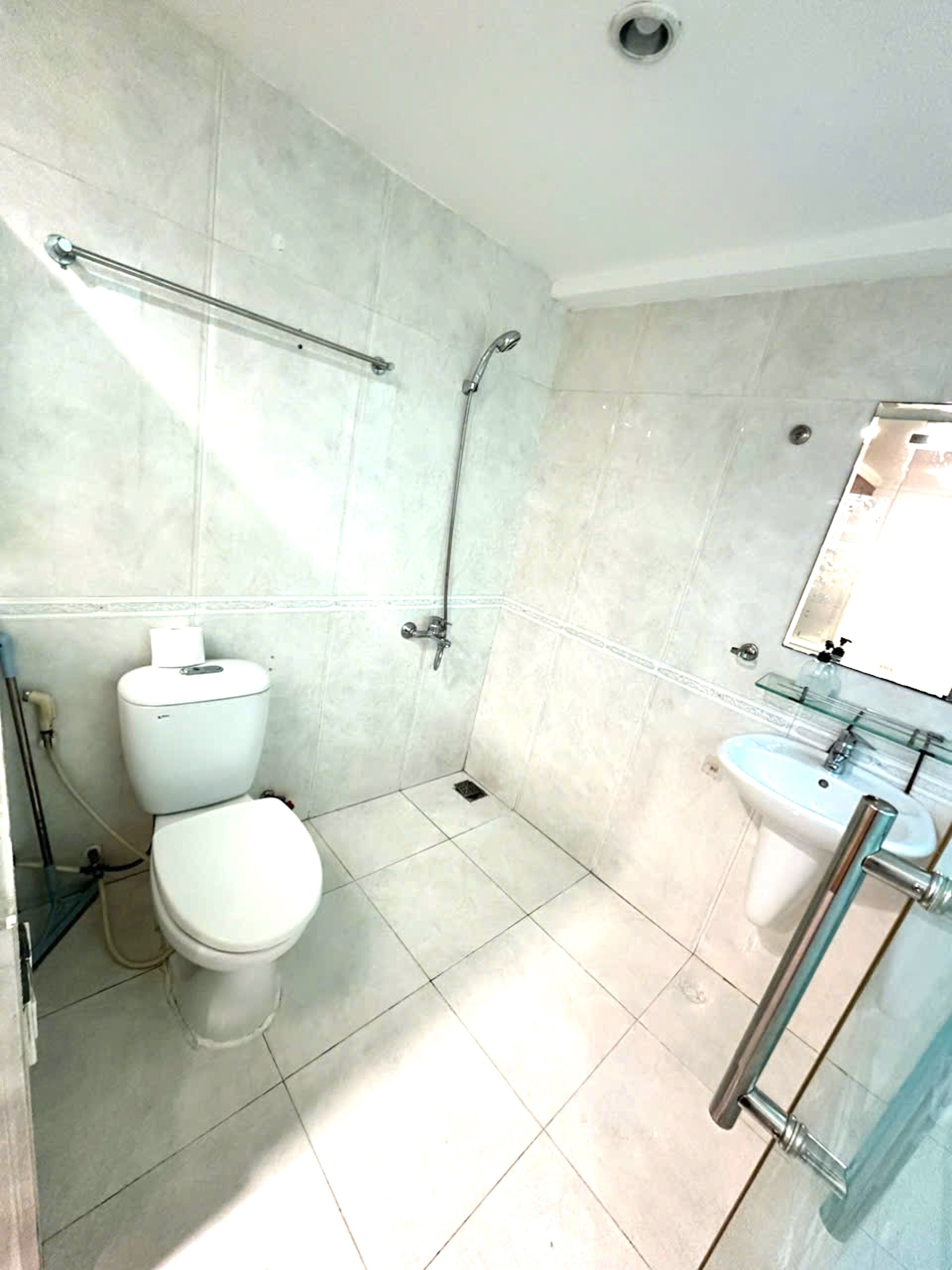 A bathroom with a toilet, shower, and sink.